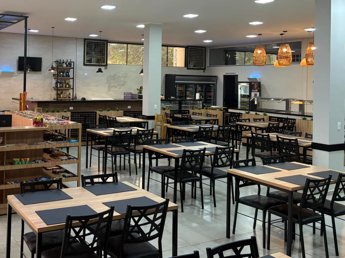Mesas do salão do Restaurante Virmond com luminárias de palha e o buffet ao fundo